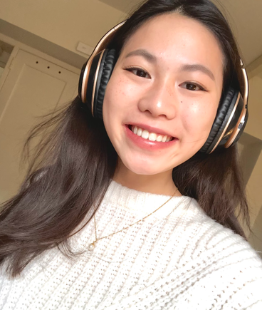 A smiling University of Minnesota student wearing headphones and a white sweater.